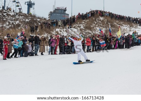 Novosibirsk, Russia - December 7, 2013 : , young man snowboarding with the Olympic torch for the Olympic torch relay in Novosibirsk