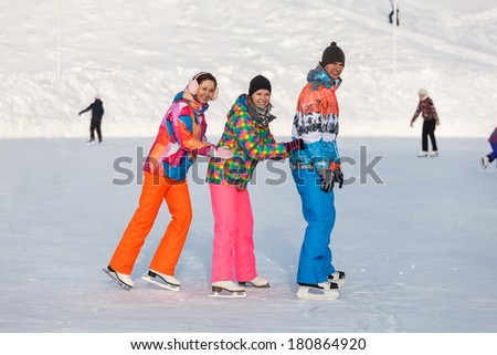 Young people, friends, ice-skating winter and recreation on the frozen lake
