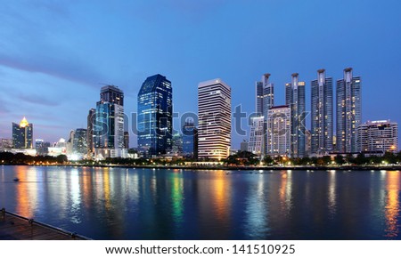 Skyscraper, tall building, business tower, panorama scenery view at downtown, City center at Sunset, evening to twilight night with reflection on lake or river, Bangkok, capital city of Thailand