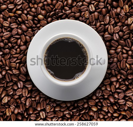 Bird eyes view of coffee cup on raw coffee beans. Top view of cup of hot coffee on roast coffee bean
