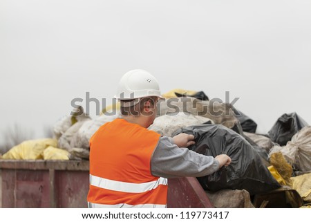 Worker with garbage and debris bags to a container