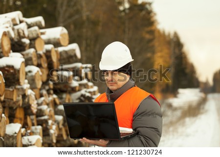 Forester with the computer near the log pile