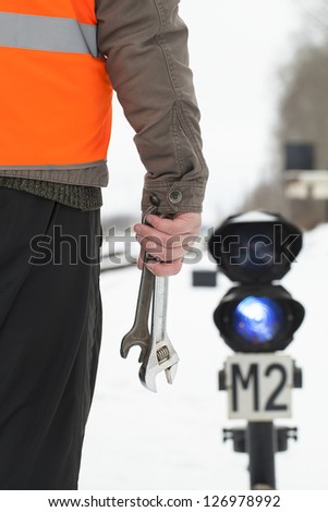 Man with adjustable wrench in the hand on the railroad