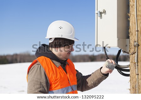 Electrician with electrical cable in the hands near switchboard