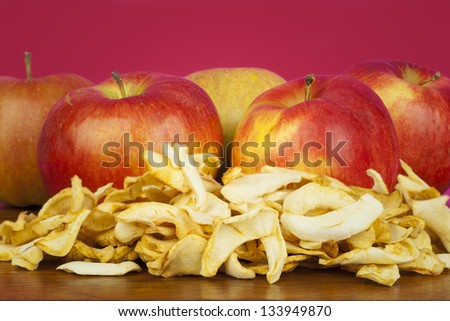 Dried apple slices ??on a table with the fresh apples on the background