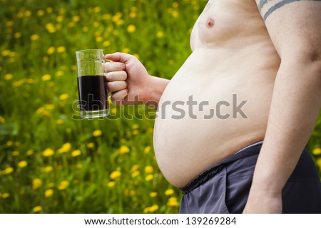 Fat man with a beer in hand on dandelion field background