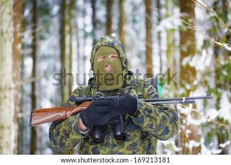 Hunter with optical rifle and binoculars forest in the winter