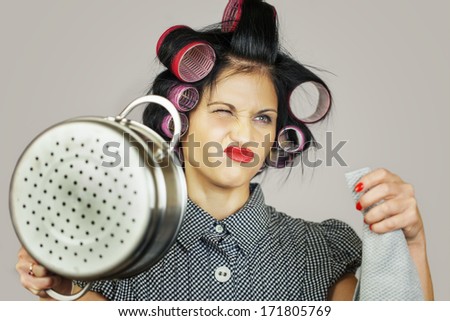Housewife with a kitchen pot on grey background