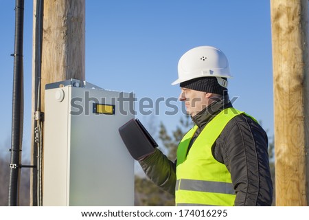 Electrician with tablet PC inspect electric lines
