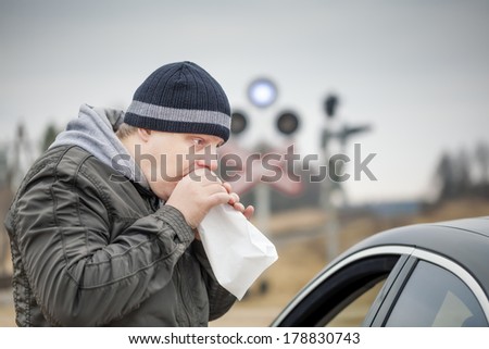 Worried man breathe into a paper bag near rail crossing