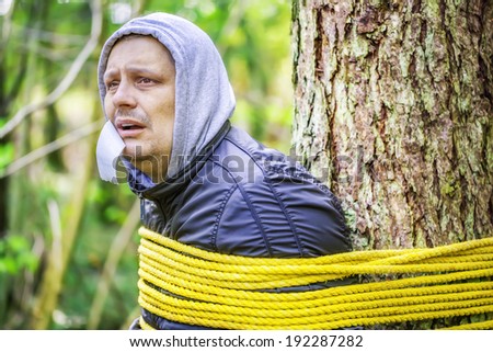 Man tied to a tree in the forest