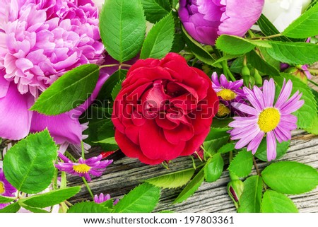 Rose with a variety of flowers on old wooden board