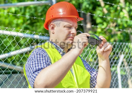 Worker with  sunglasses near the fence
