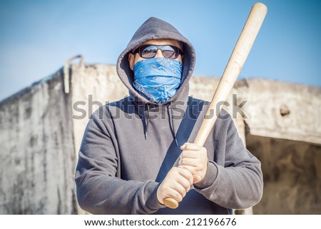 Aggressive man with a baseball bat on building background