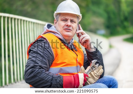 Worker with wrench and a telephone on the bridge