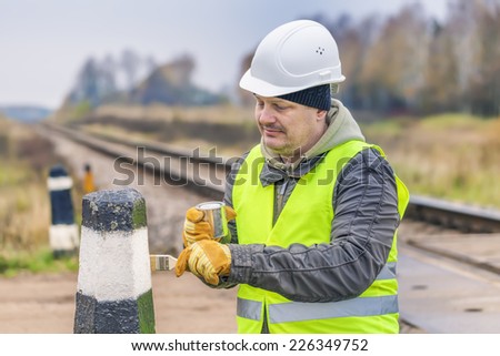 Worker with brush and paint on the railway crossing