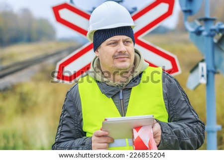 Railway engineer with tablet PC near warning signs