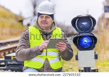 Railway employee with tablet PC near the warning lights