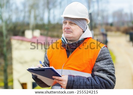 Construction employee with  documentation near building