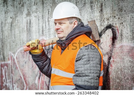 Worker with sledge hammer near the wall