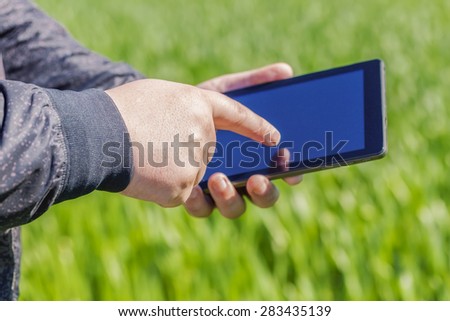 Hand with tablet PC on cereal field