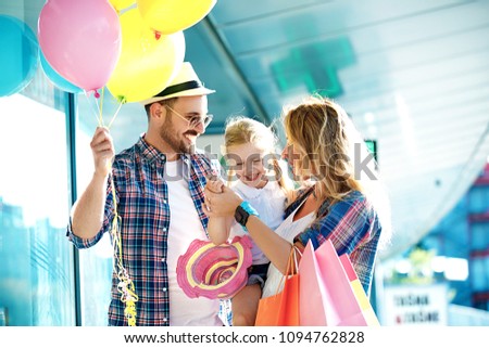 Happy family walking along the shopping mall with shopping bags and balloons.