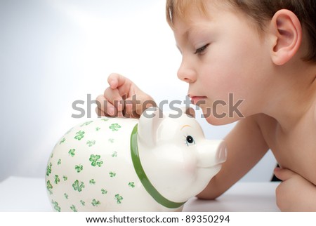 young child , boy saves change in his piggy bank
