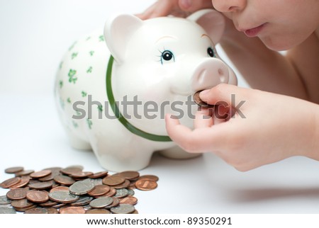 young child , boy saves change in his piggy bank