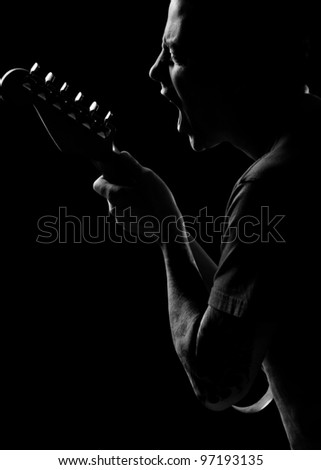 black and white of caucaision male sings to his guitar