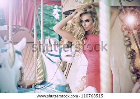 Fashion model posing on carousel in pretty summer dress