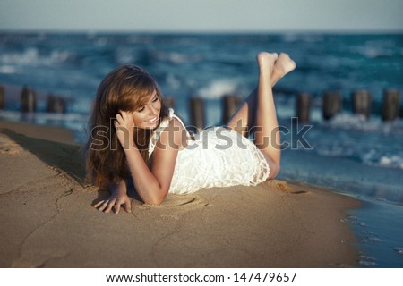 Happy beauty young woman lying on the beach