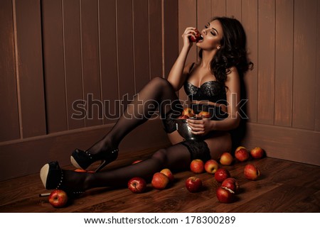 Sexy beautiful girl sitting on a floor with apple in the hand.