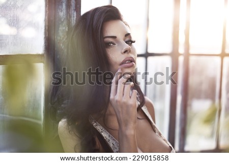 Photo of beautiful young brunette girl smiling, posing with her hands in hair.