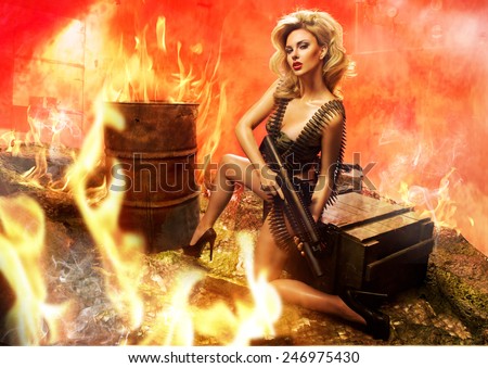 Sexy blonde woman with rifle in fire