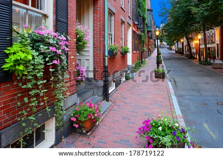 Narrow street in Beacon Hill, Boston. Flowers on window box, planters on brick sidewalk and old fashioned street lamps