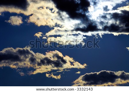 Dramatic blue sky with backlit cloudscape and white sun disc