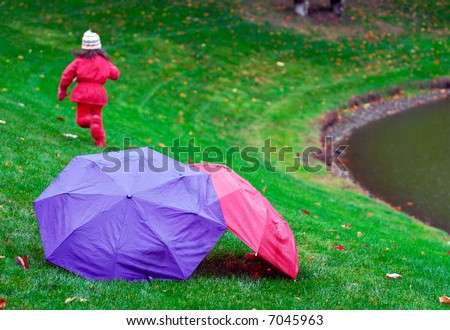 Little girl running in the rain away from red and purple umbrellas