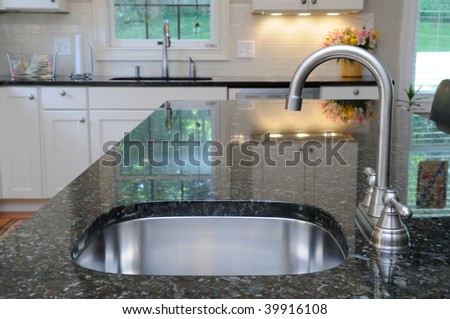 Modern stainless steel faucet and sink on kitchen island. Elegant granite counter.