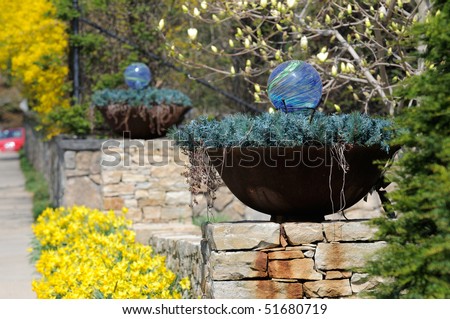 Planter or flower pot with garden ornaments on stone wall