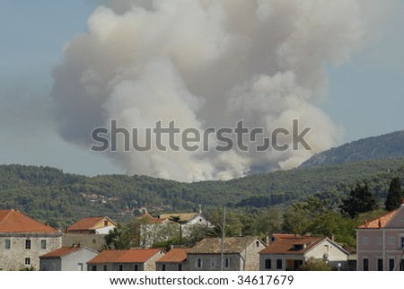 Mediterranean forest fire with smoke cloud over the city