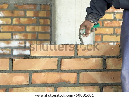 A brick layer putting down another row of bricks