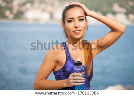 Fitness Beautiful Woman Drinking Water And Sweating After Exercising On Summer Hot Day In Beach. Female Athlete - Work Out.