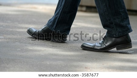 Man shoes walking in the street. Focus on the right shoe