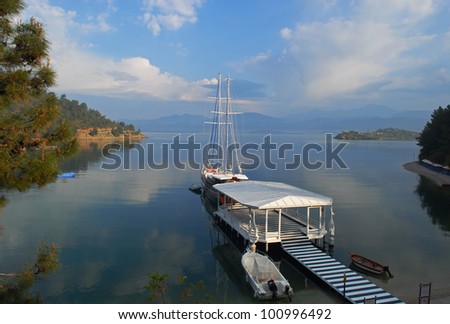 Chic yacht lie up near the mooring berth.  Mountains outline are in the background.