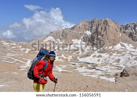 The hiker dressed in bright closes stands at a high mountains. This is  Anti-Taurus Mountains (Aladag?lar) - Turkey.