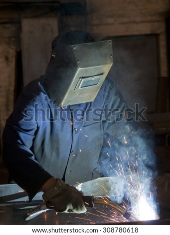 Working man with helmet shield on his head is welding  steel construction. Story about weldor profession.