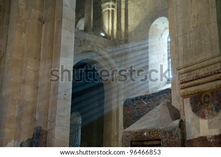 This is indoor scene of ancient  Svetitskhoveli Cathedral in Mtskheta. Shoots of sunlight penetrate interior space of church.
