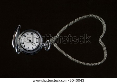 Silver pocket watch and a chain from watch in the form of heart on a black background