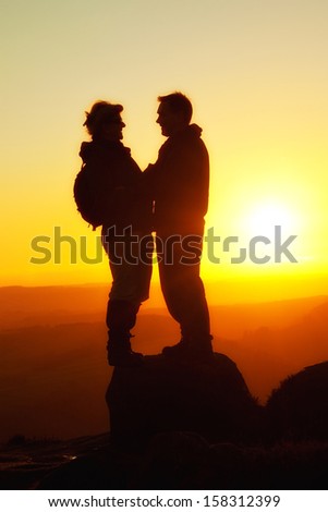Two walkers stand face to face Silhouetted at sunset