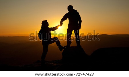 A loving couple walking holding hands Silhouetted by the sunset